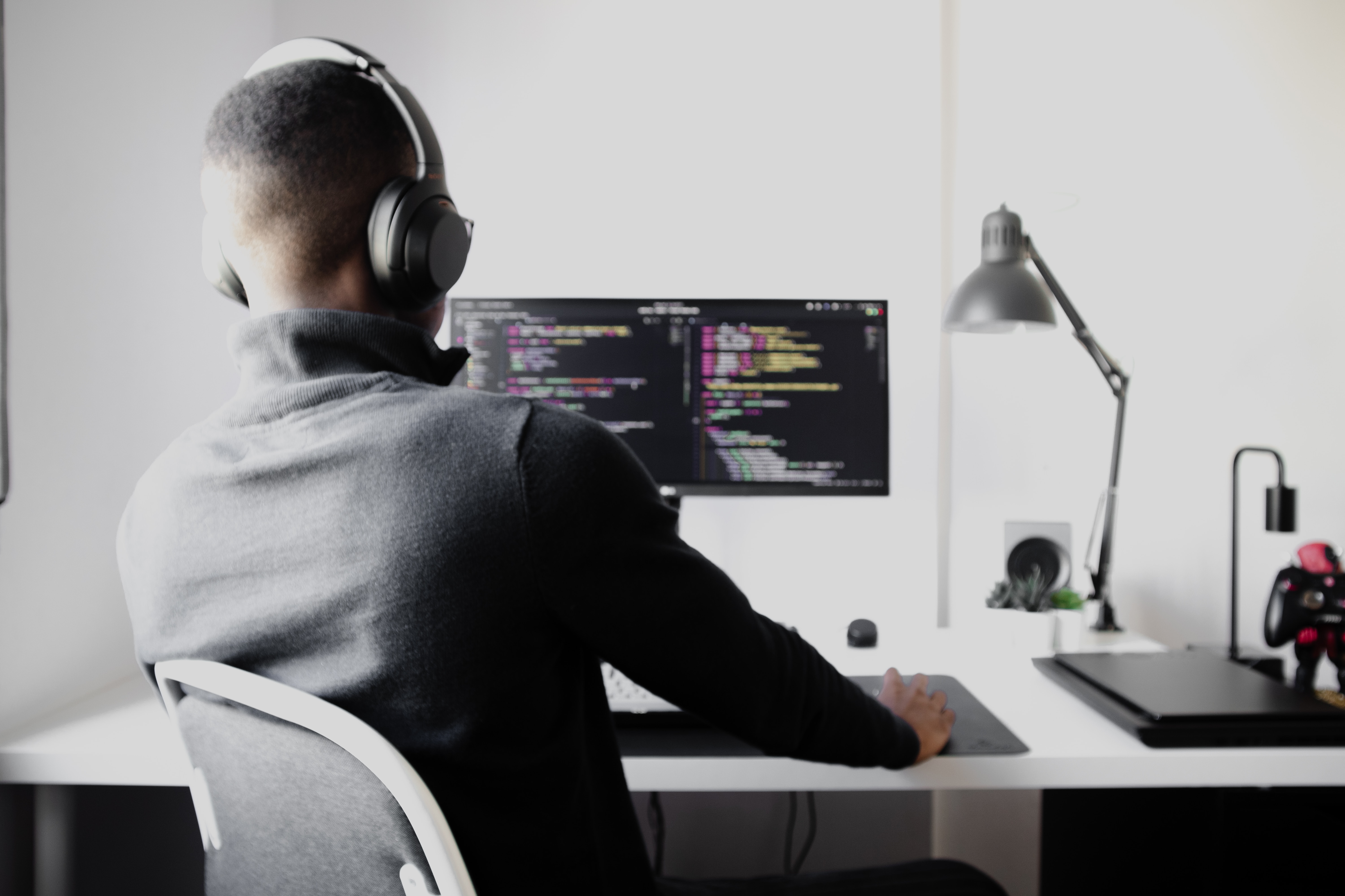 Man with headphones on at computer coding
