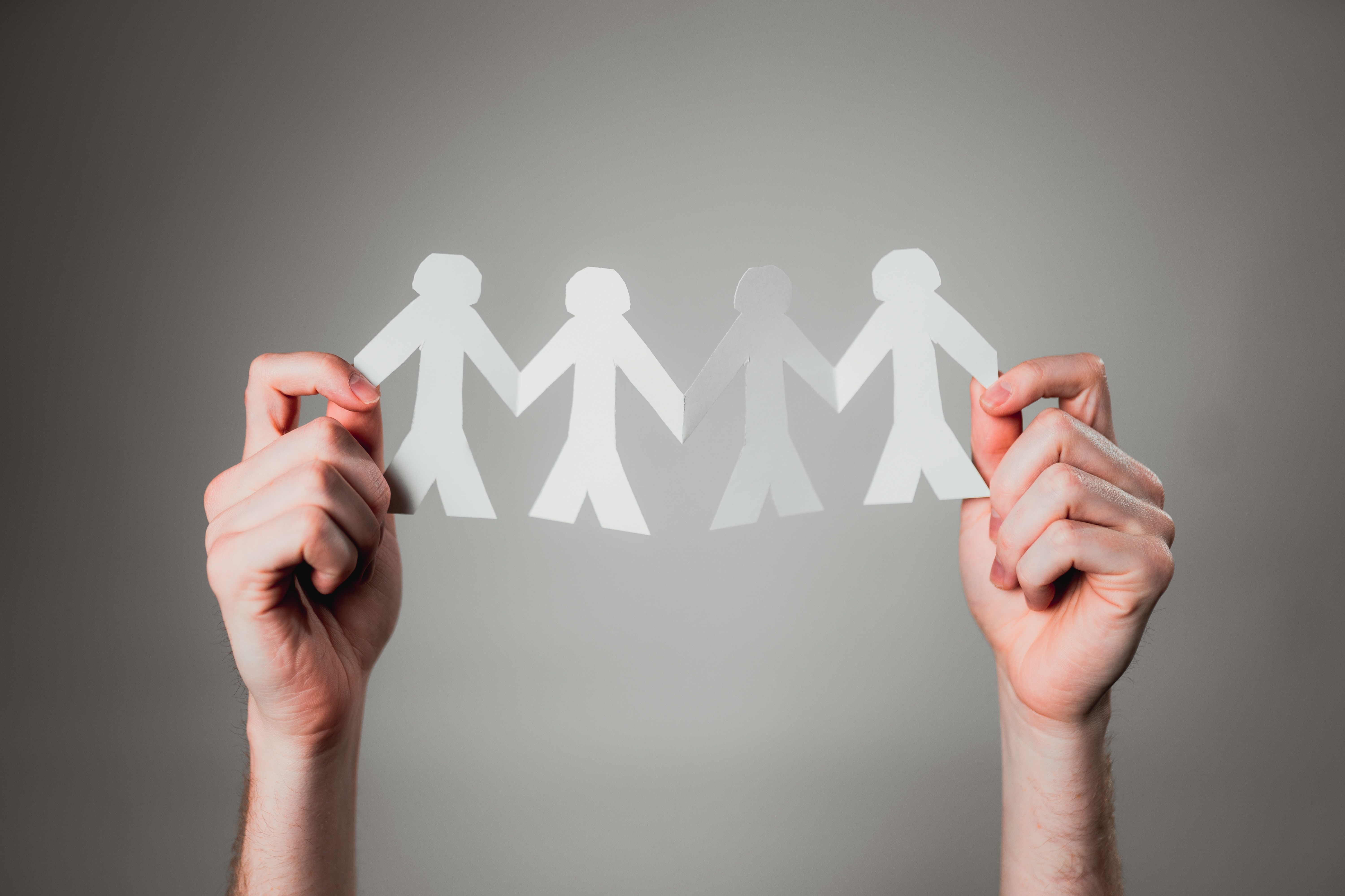 hands holding up a human paper chain