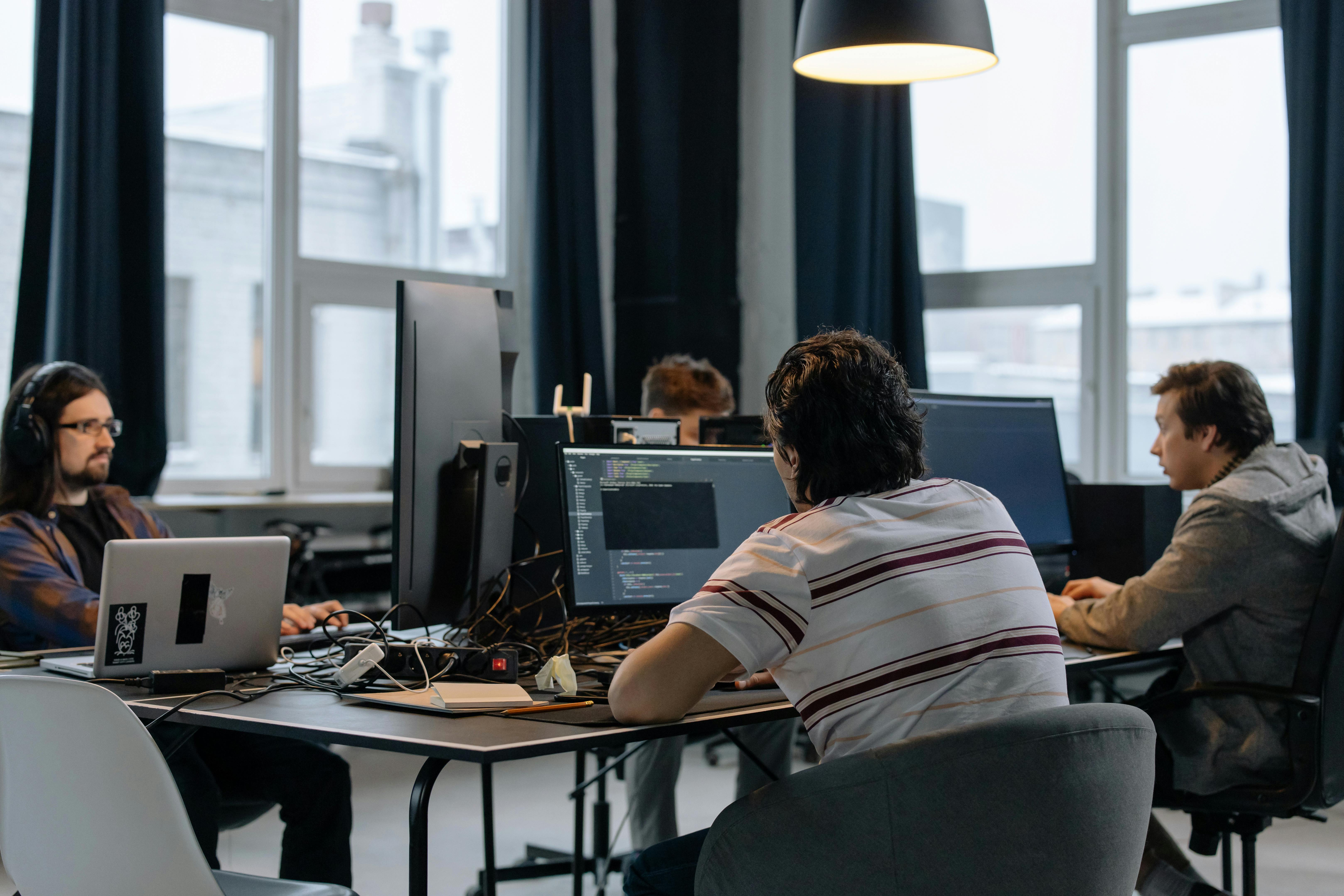 four people working on computers around a desk