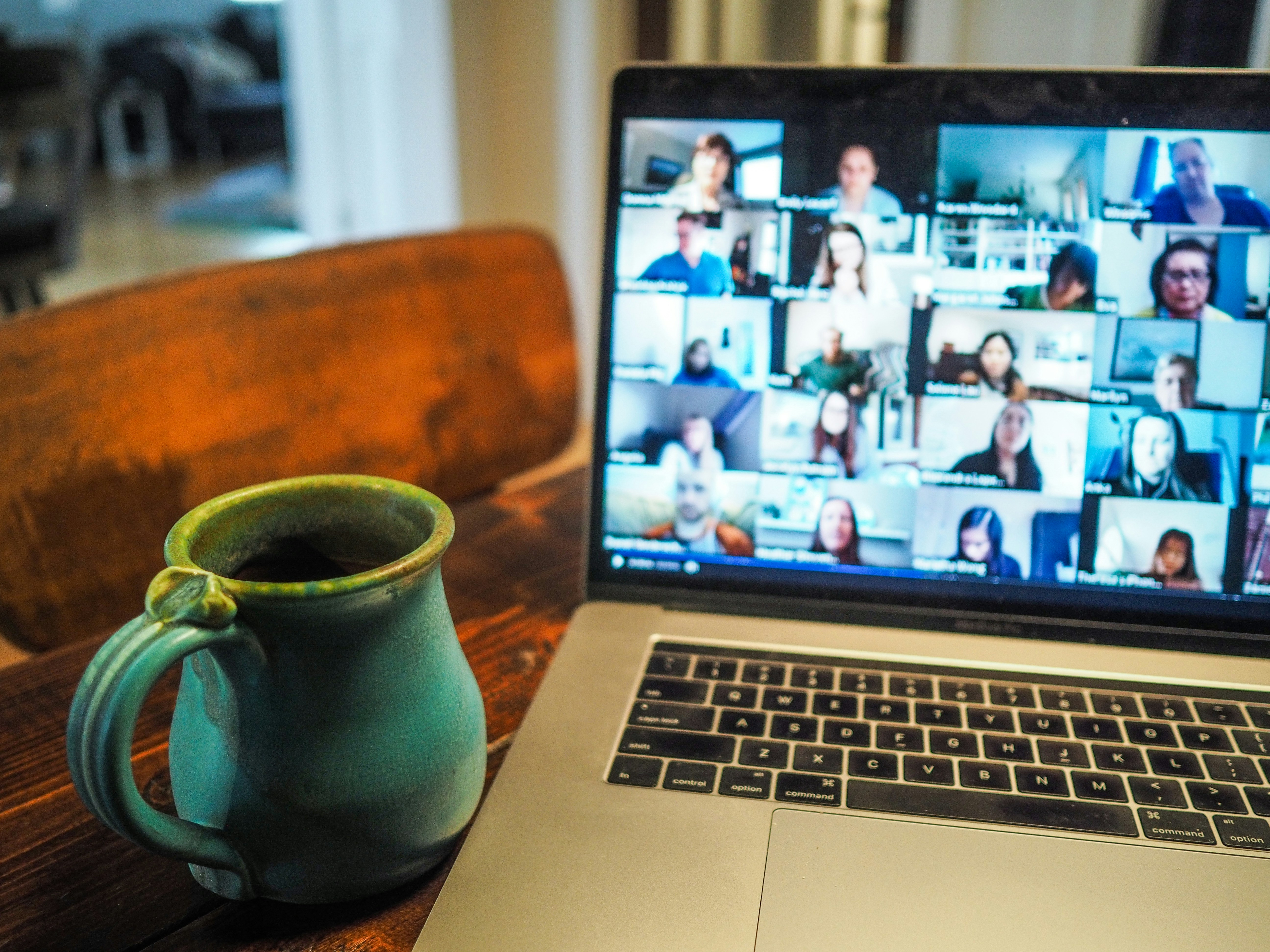 Zoom meeting shown on screen of laptop & a coffee mug