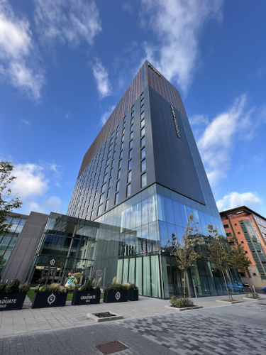 Photo of tall hotel with glass windows and tress in front 