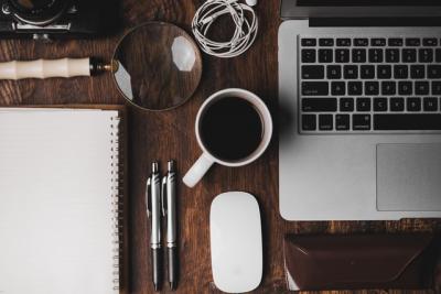 Desk with computer, coffeemug, notebook, pens