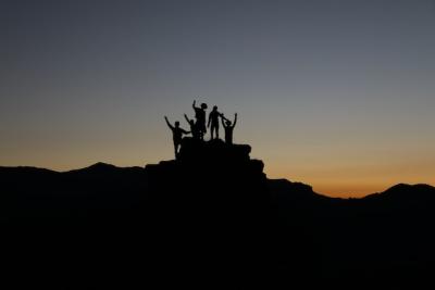silhouette of people standing on top of a hill