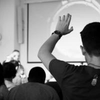 man with raised hand in classroom