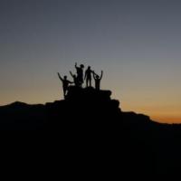 silhouette of people standing on top of a hill