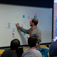 man adding post its to whiteboard